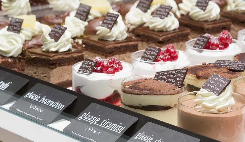 Glaasjes tiramisu, mousse en gebakjes in de koeltoog, elk met een naambordje